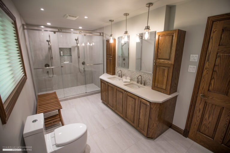 Rénovation de salle de bain haut de gamme à Montréal avec vanité en bois conservée et grande douche vitrée sur mesure.
